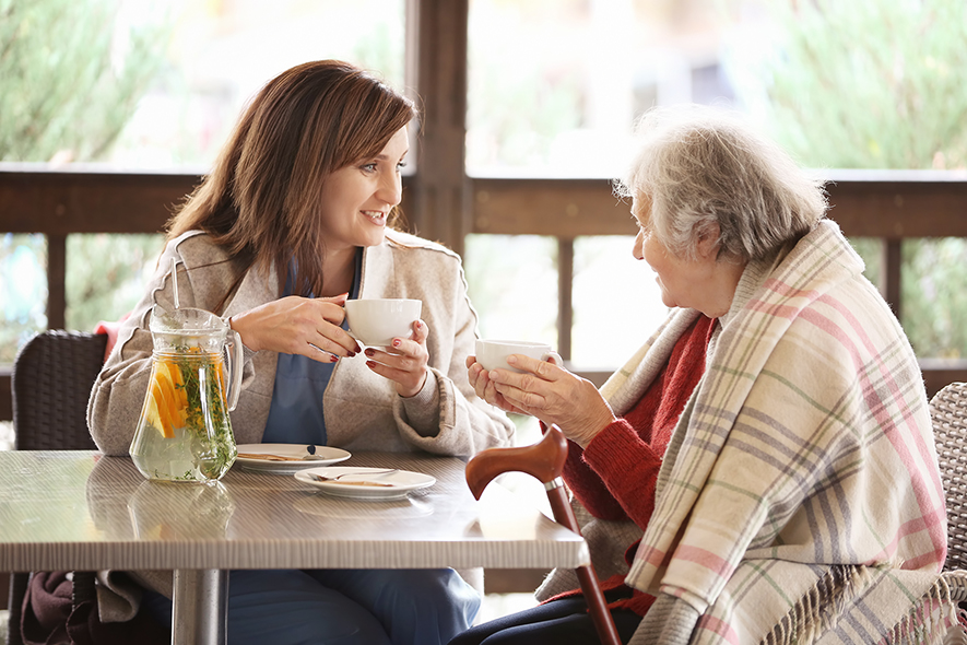 Caregiver having homemade tea with a elderly patient.