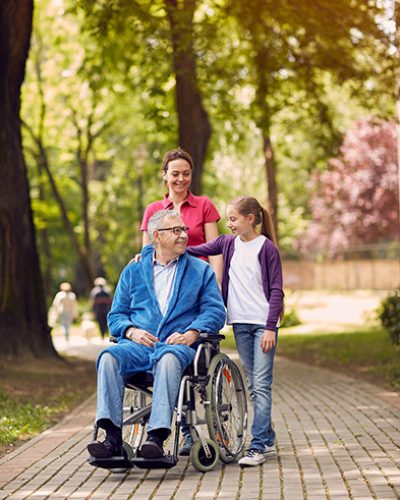 Disabled man in park spending time together with caregiver and his granddaughter